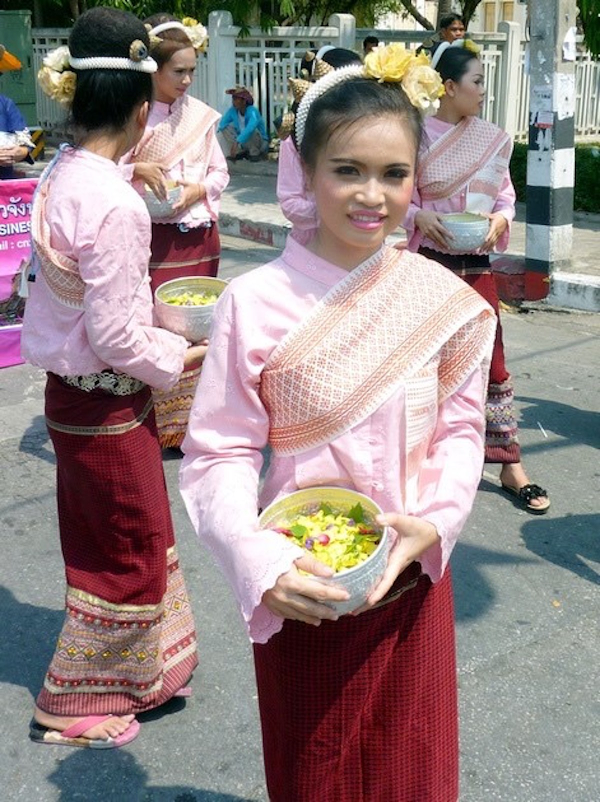 A pretty Thai lady in traditional dress smiles at the camera 
