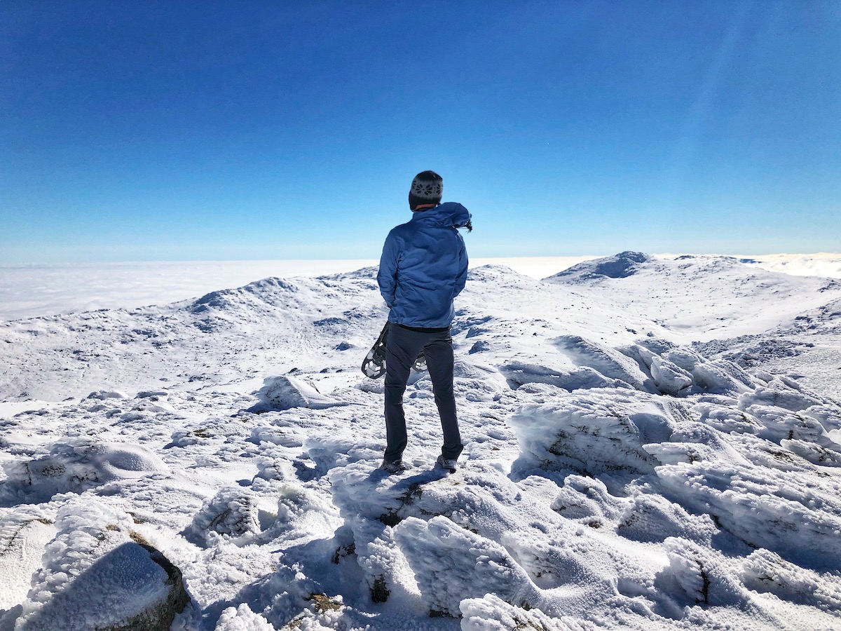 How To Plan The Ultimate Australia Road Trip in 2024 • Kosciuszco national park australia road trip A man standing on top of a snowy mountain holding ski shoes.