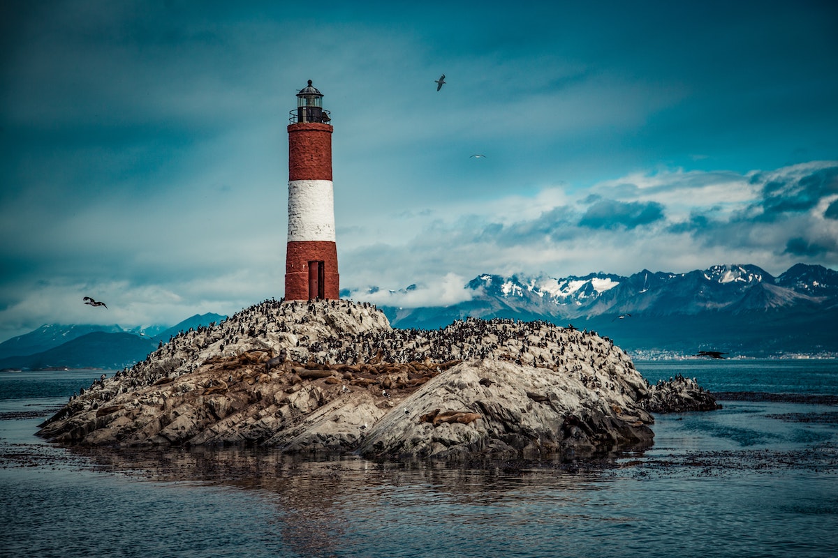 A red and white lighthouse on a body of water 