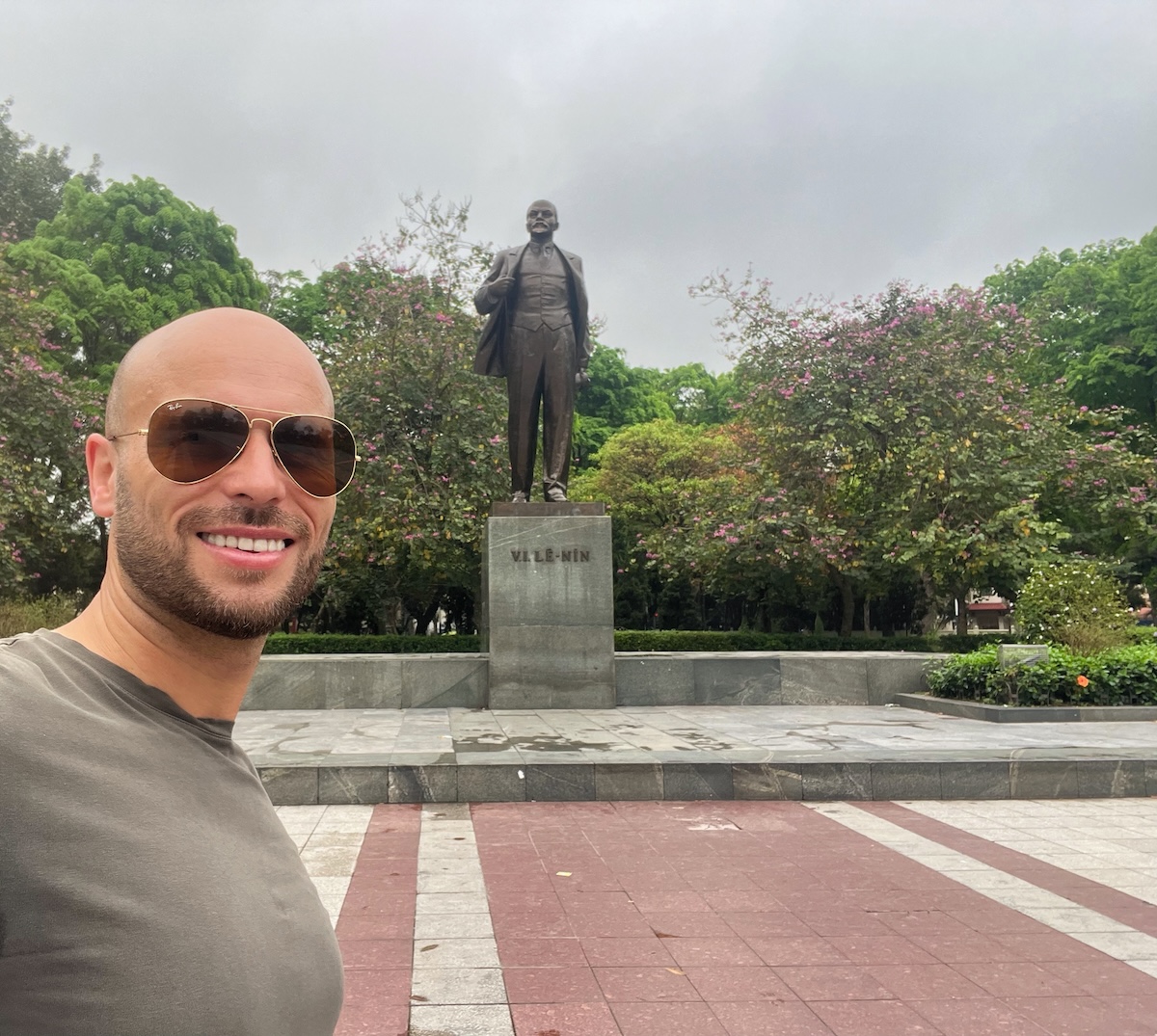 A tourist poses in front of a statue of Vladimir Lenin in Hanoi, Vietnam