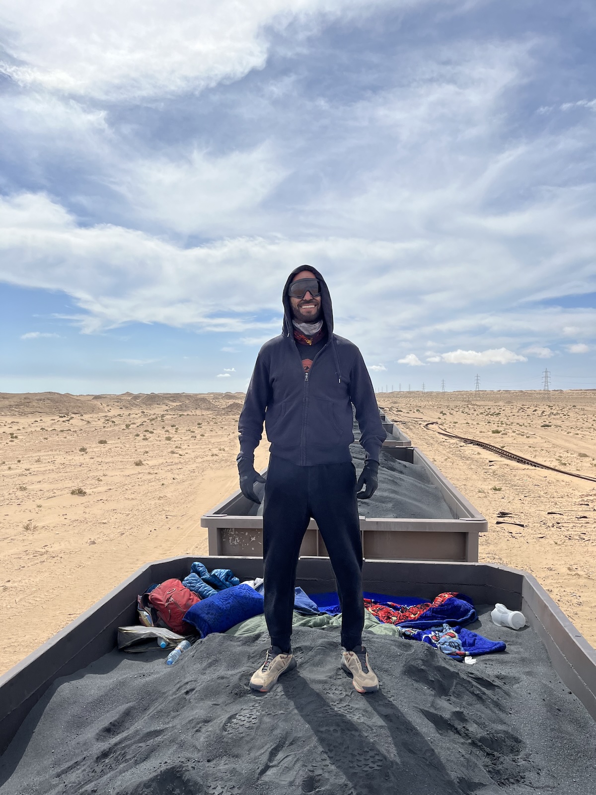 A man in sunglasses smiles while standing on the Iron Ore Train in Mauritania 