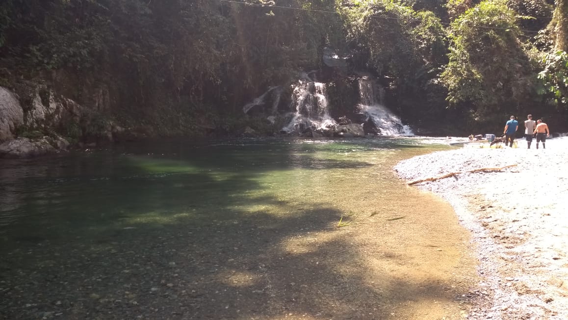A group walk past an emerald river
