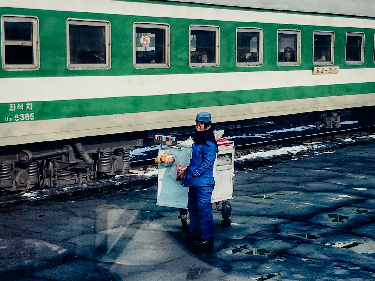 A man wrapped om blue cold weather clothes sells food on the border of China and North Korea
