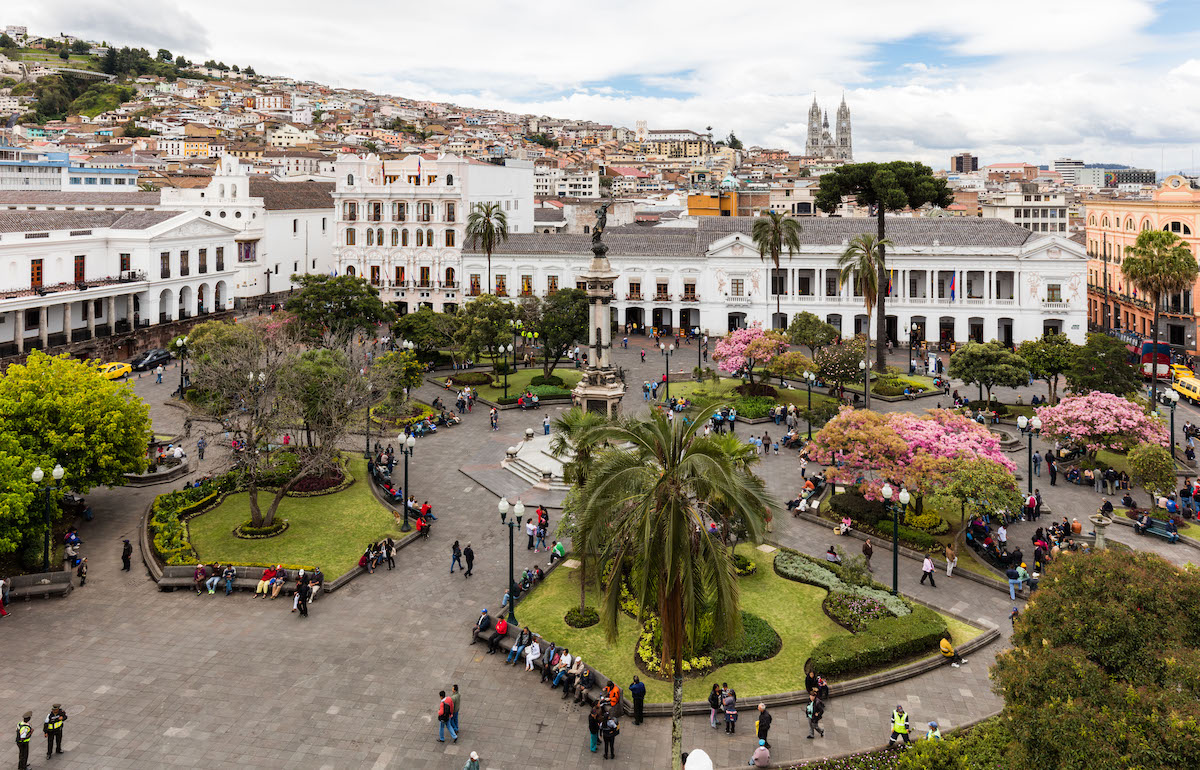 A busy park overlooking a white building in Quito, Ecuador.