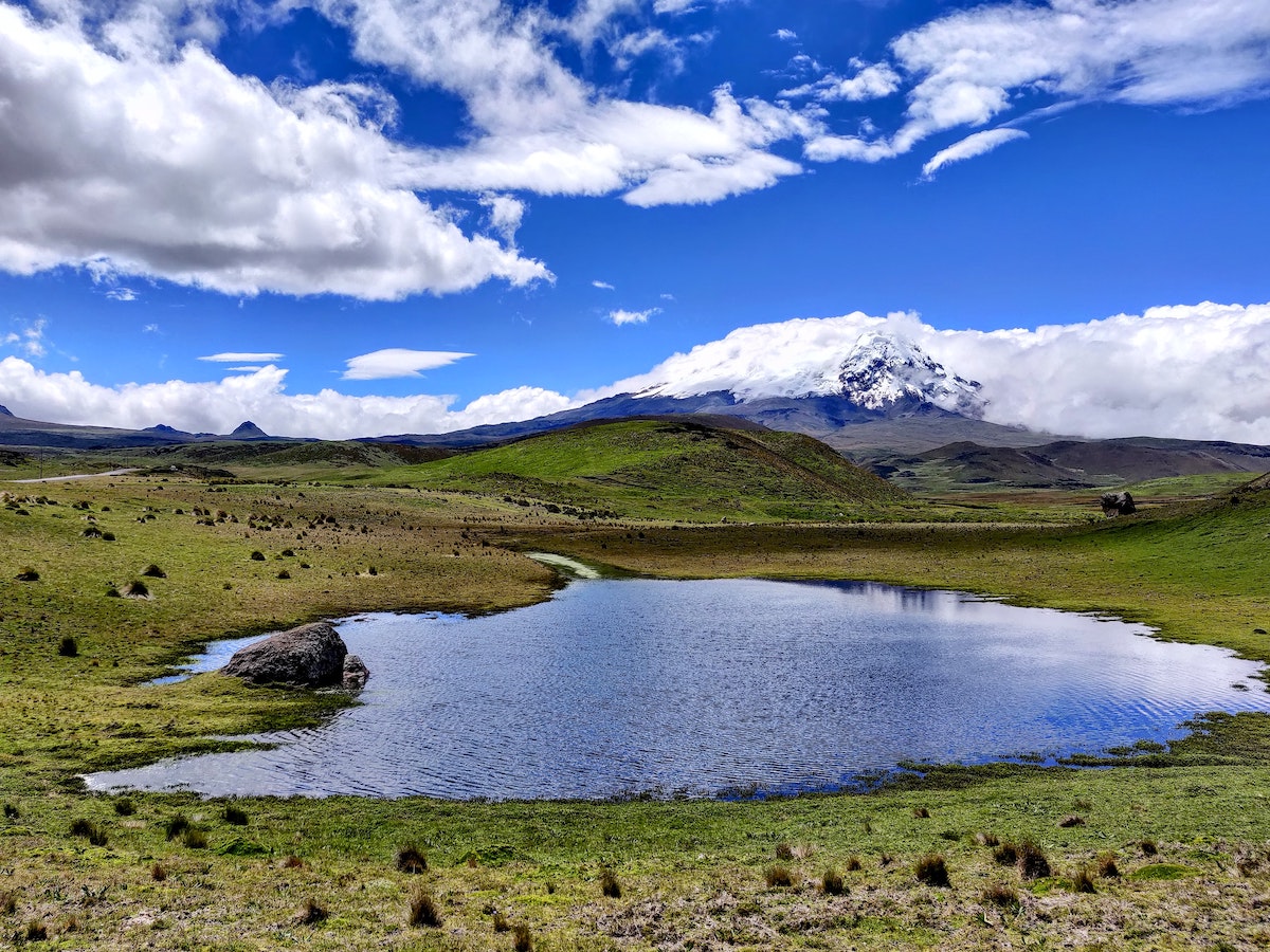 A frosted mountain in the distance of a large green plain in Ecuador.