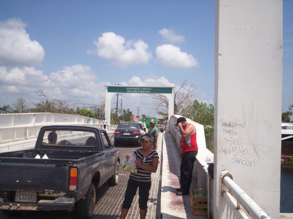 A female vendor sells fruits at a bridge crossing