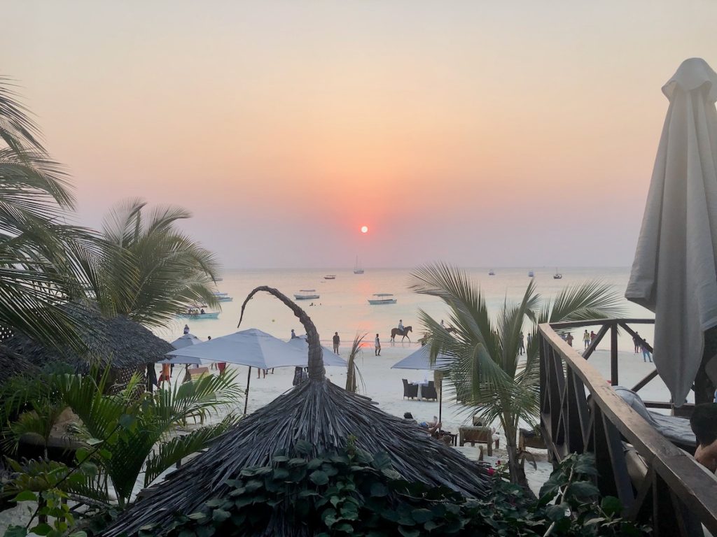 A stunning sunset overlooking a bamboo roof and a busy ocean
