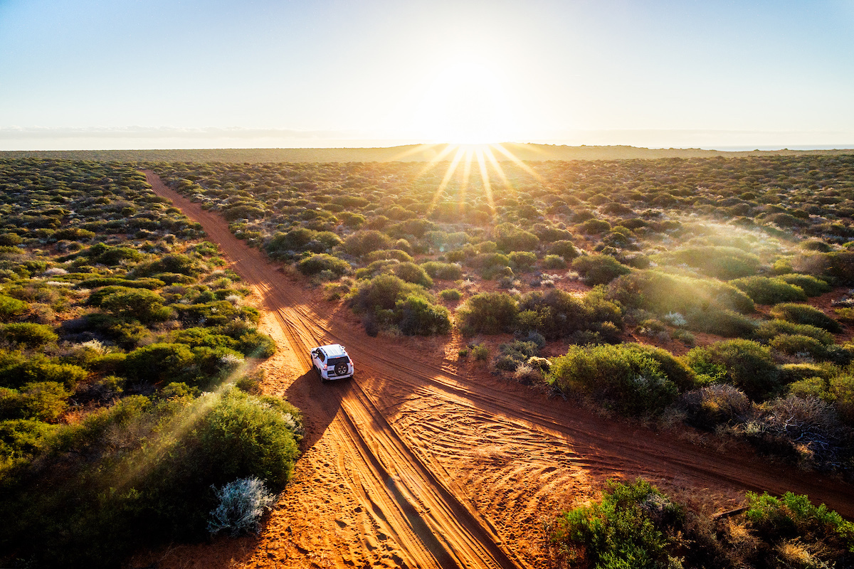 How To Plan The Ultimate Australia Road Trip in 2024 • campervan in australia A campervan driving through the desert on a sunny day in Australia.