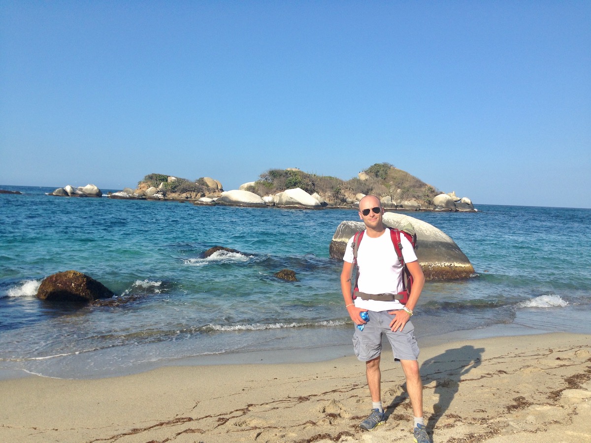 Hiker poses on a beach while hiking in Tayrona National Park in Colombia. 