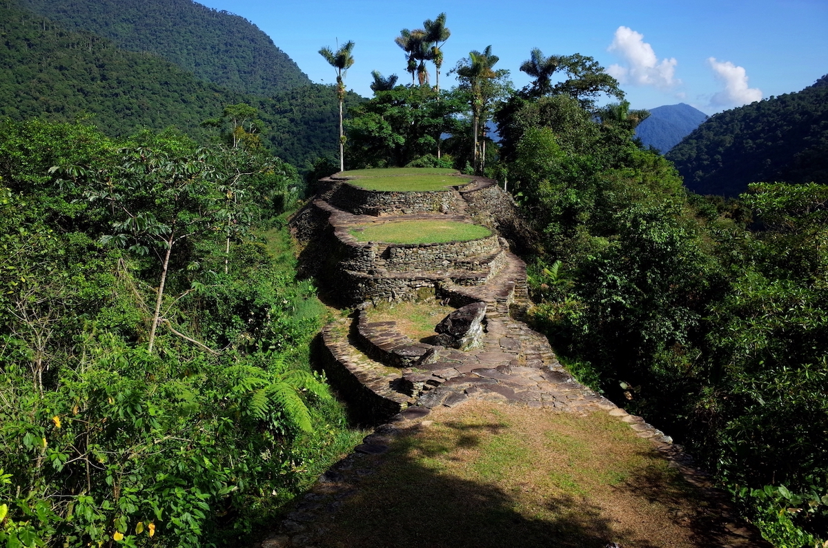 Ancient ruins surrounded by greenery on a clear blue sky day.