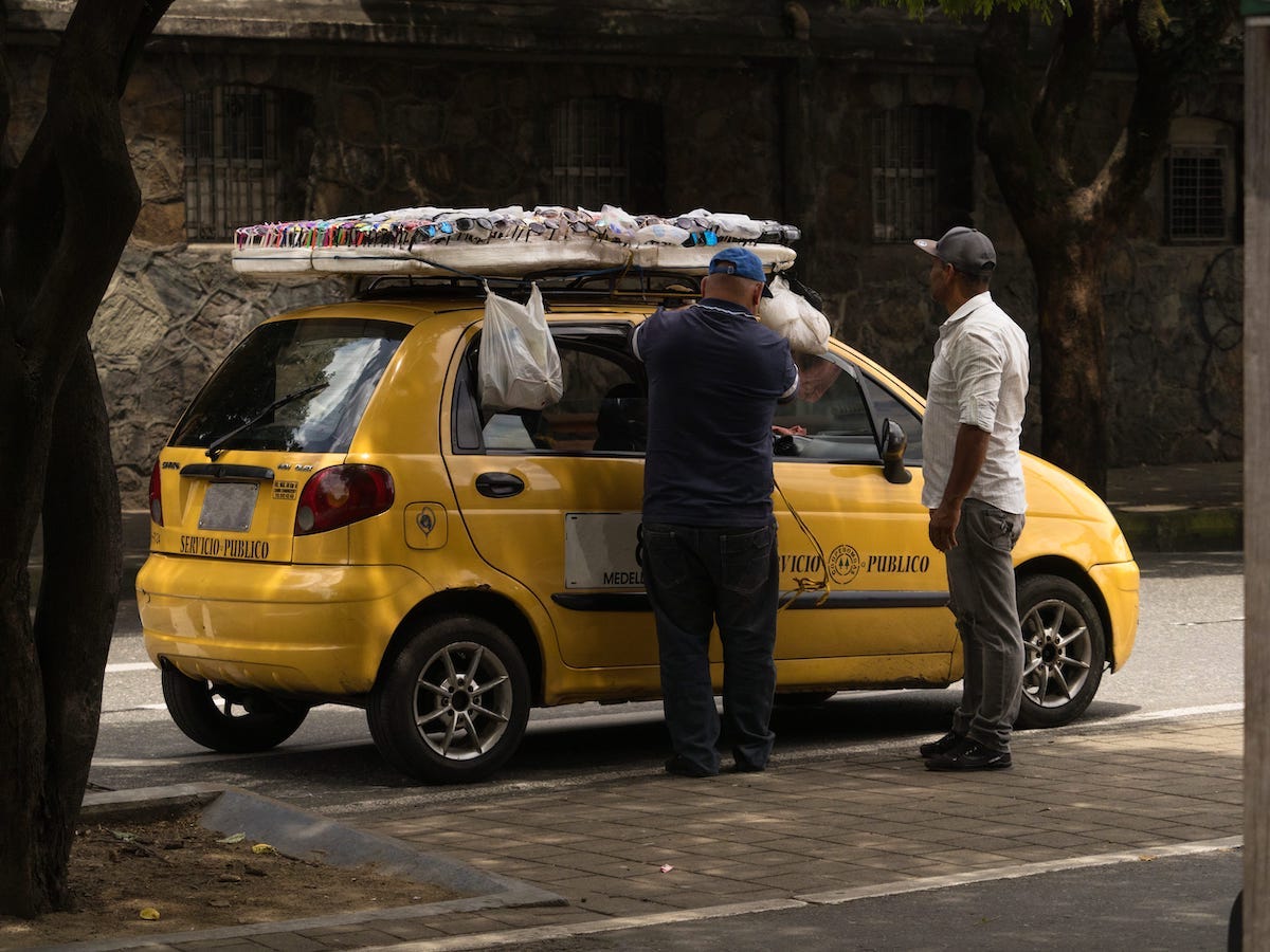 Taxi driver arranging sunglasses shades display board on car cab roof in Medellin Antioquia Colombia in South America