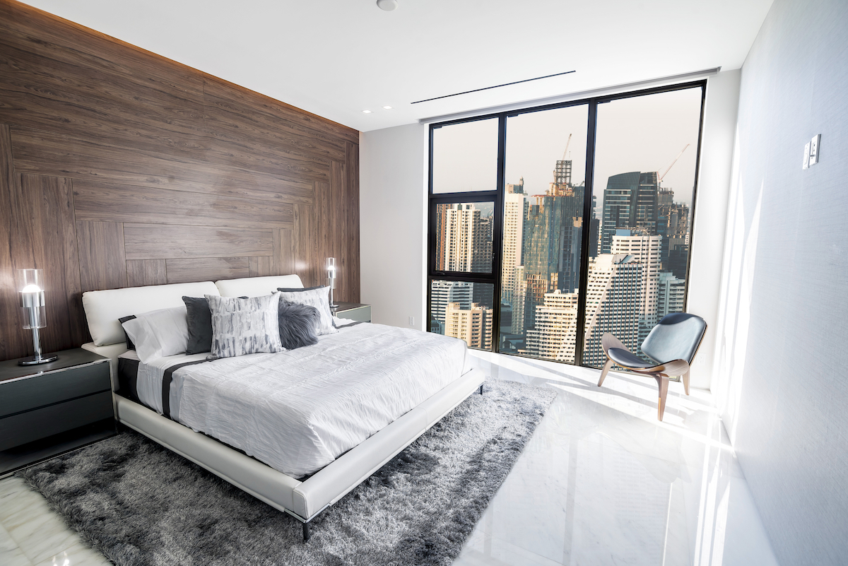 Cost of Living in Bangkok (& The Lies That Bloggers Tell) • modern Bangkok condo with city view Modern and luxurious condo bedroom with white ceiling and wood accents with views of Bangkok skyline