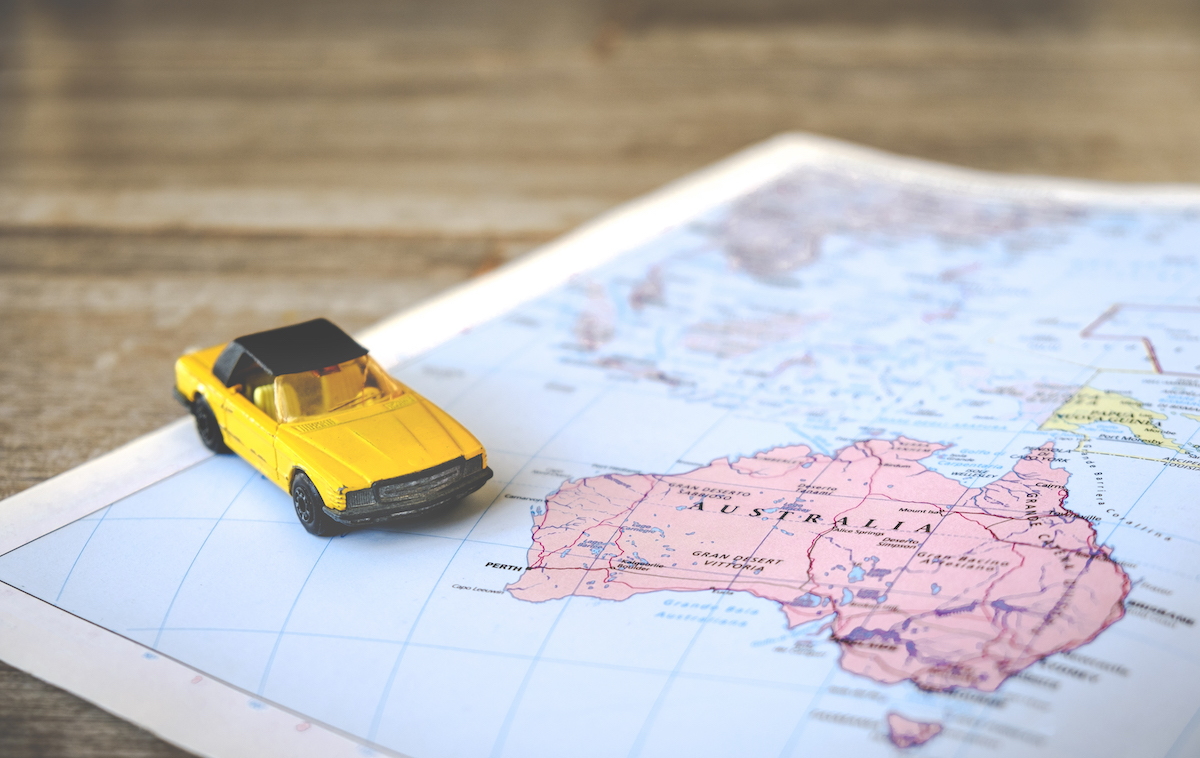 How To Plan The Ultimate Australia Road Trip in 2024 • planning australia road trip A toy yellow car on a paper map.