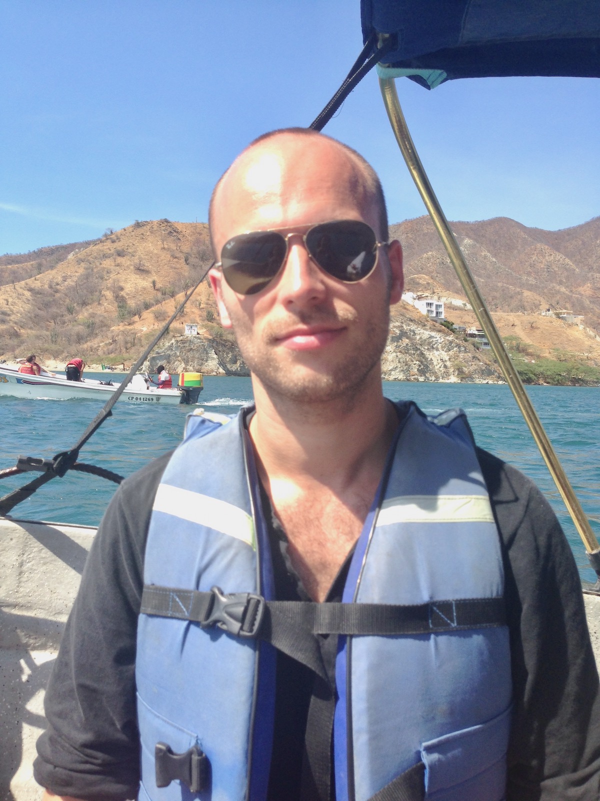 A male tourist in sunglasses poses on a boat in Taganga, Colombia. 