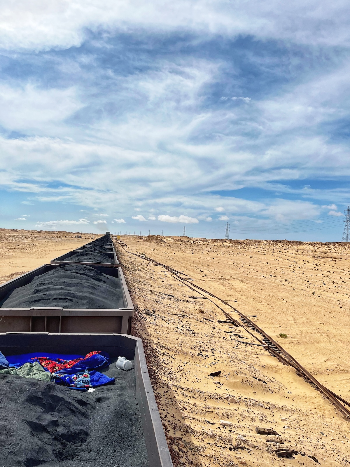 A long train carrying iron ore rides over the desert
