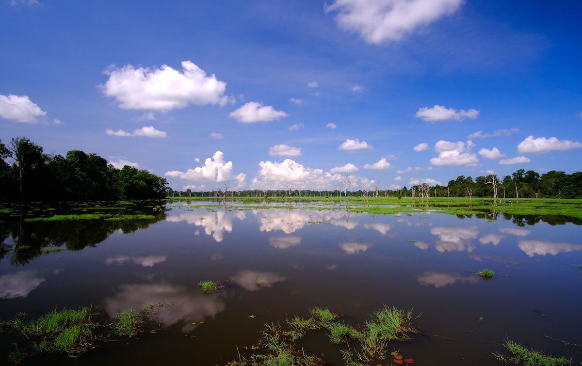 The cloudy sky reflects off a large lake. 